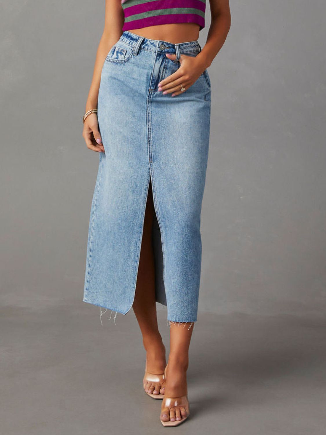 "Raw hem front slit denim midi skirt with a trendy, edgy look. Features a front slit for movement, and a raw hem for a chic, unfinished style."