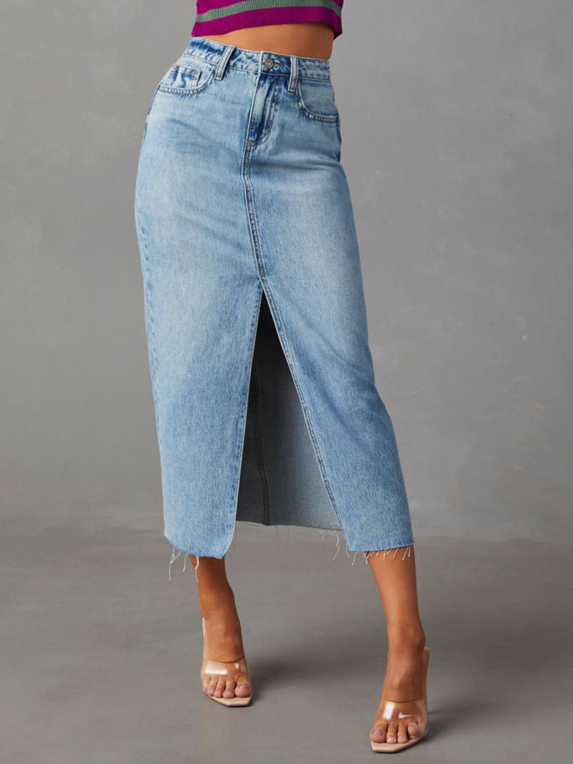 "Raw hem front slit denim midi skirt with a trendy, edgy look. Features a front slit for movement, and a raw hem for a chic, unfinished style."