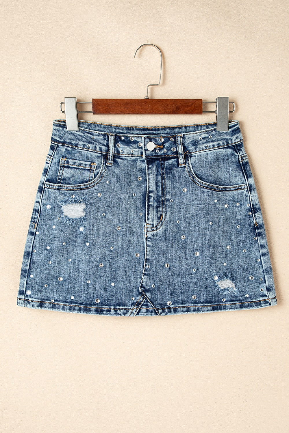 "Trendy rhinestone distressed denim mini skirt with edgy distressed detailing, sparkling rhinestones, and a flattering fit, perfect for a chic, casual look"