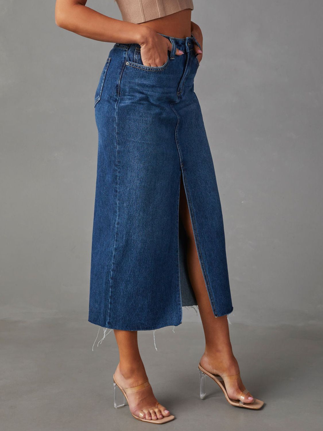 "Raw hem front slit denim midi skirt with a trendy, edgy look. Features a front slit for movement, and a raw hem for a chic, unfinished style."