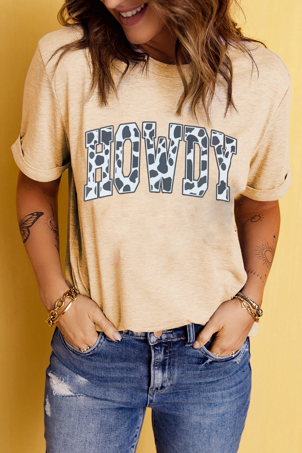 "Women's Howdy Cow Print Tee featuring a playful cow print graphic, round neckline, and short sleeves for a casual, country-inspired look."