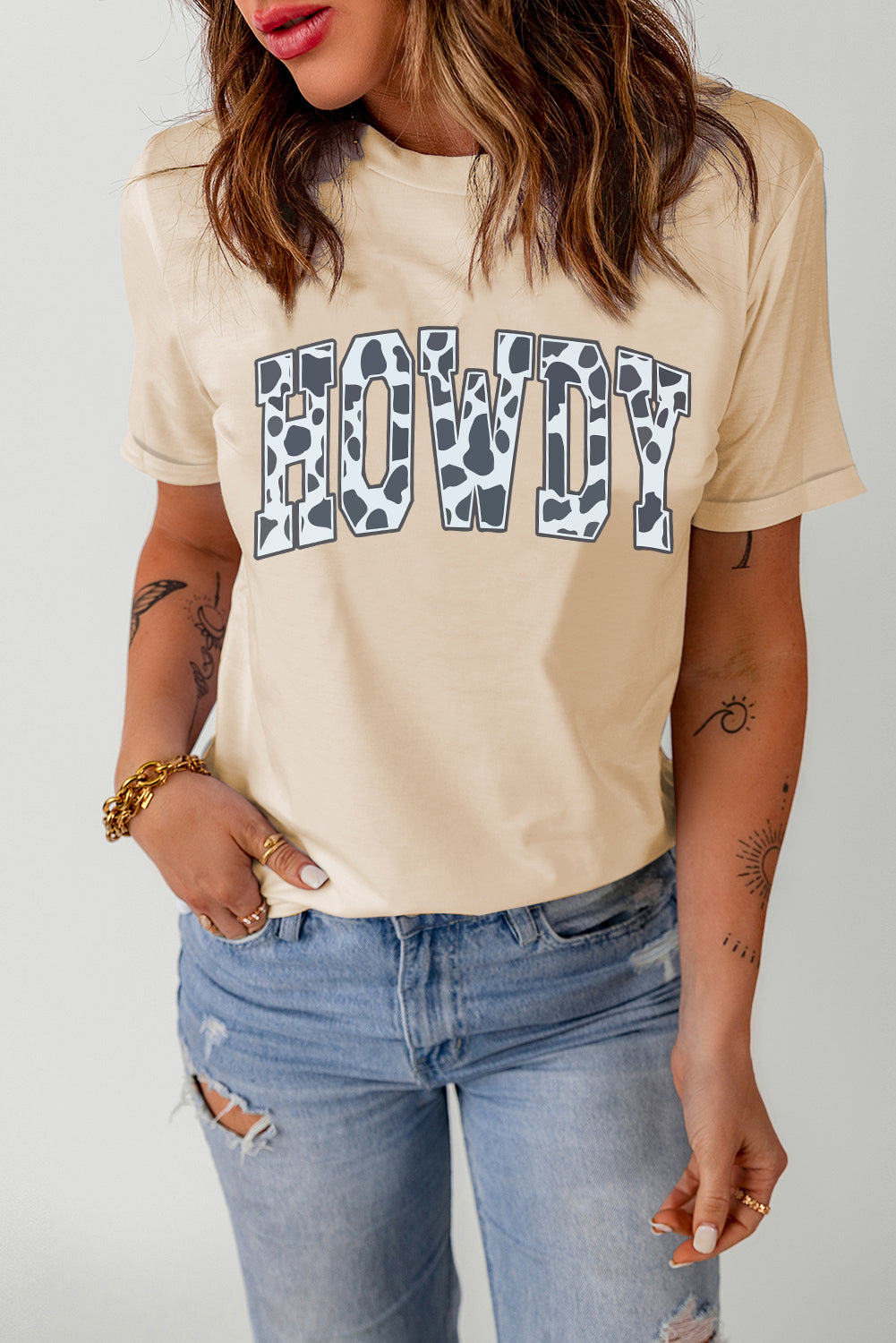 "Women's Howdy Cow Print Tee featuring a playful cow print graphic, round neckline, and short sleeves for a casual, country-inspired look."
