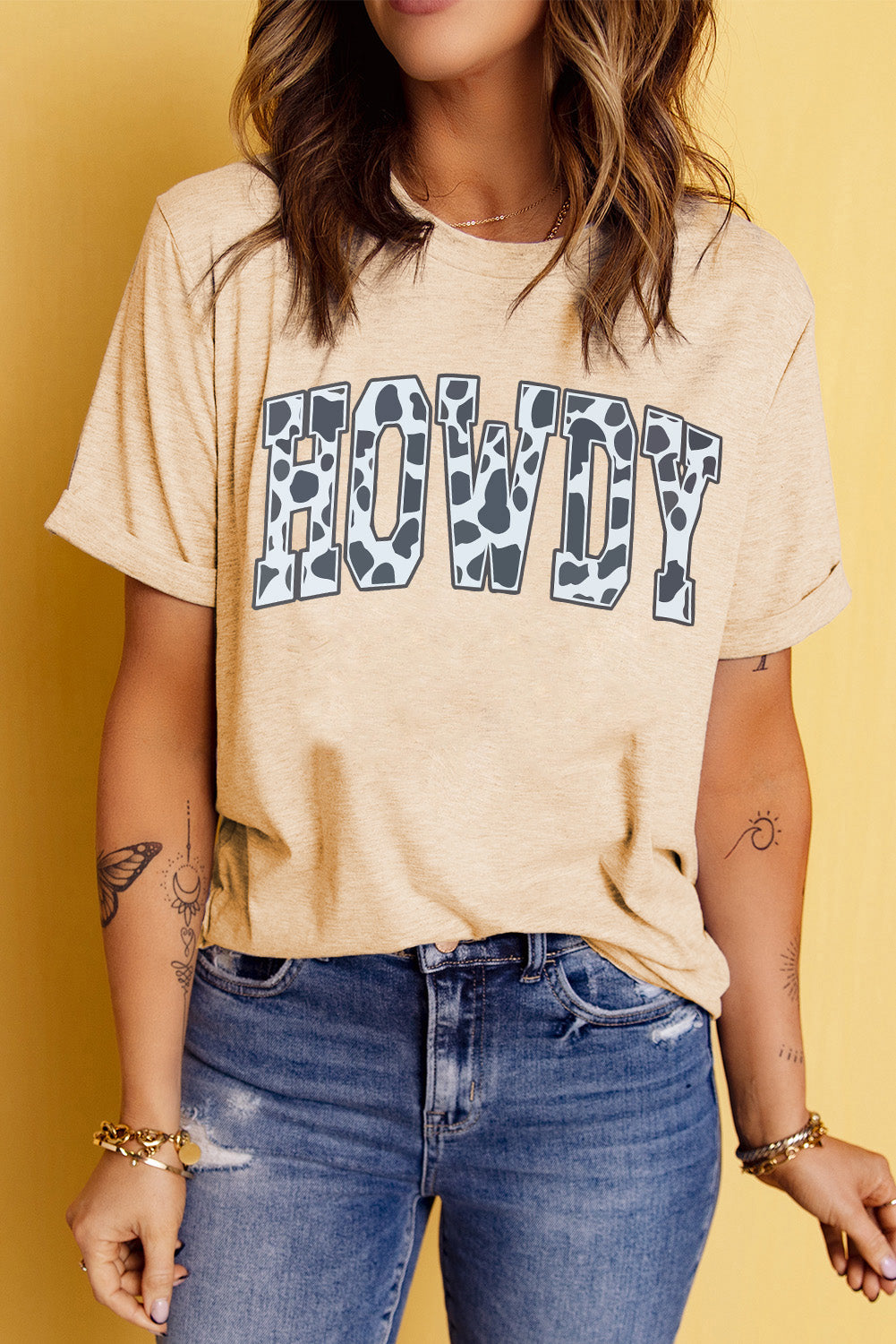 "Women's Howdy Cow Print Tee featuring a playful cow print graphic, round neckline, and short sleeves for a casual, country-inspired look."
