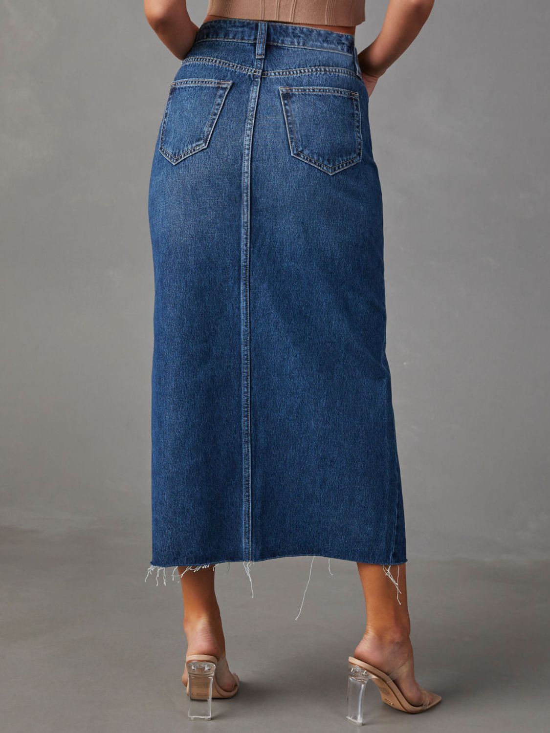 "Raw hem front slit denim midi skirt with a trendy, edgy look. Features a front slit for movement, and a raw hem for a chic, unfinished style."