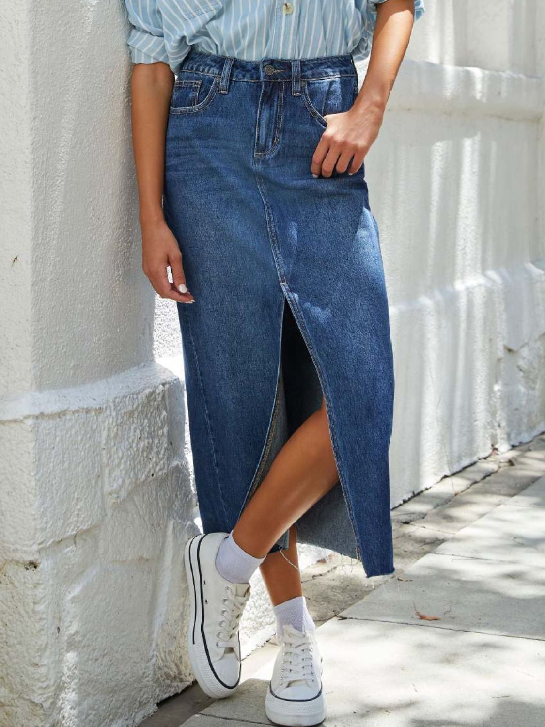 "Raw hem front slit denim midi skirt with a trendy, edgy look. Features a front slit for movement, and a raw hem for a chic, unfinished style."